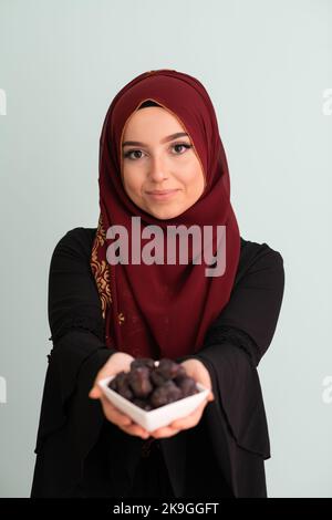 femme musulmane moderne tenant une assiette remplie de dates sucrées à l'heure de l'iftar dans le ramadan kareem concept islamique de nourriture saine Banque D'Images