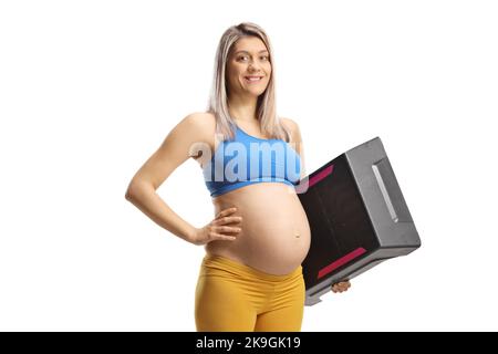 Femme enceinte souriante dans des vêtements de sport tenant une plate-forme aérobie STEP isolée sur fond blanc Banque D'Images