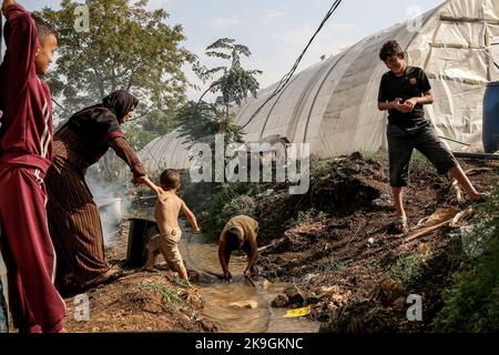 Bebnin, Liban. 28th octobre 2022. Une mère syrienne arrache son fils à jouer dans un conduit d'eau contaminée près de leur tente dans un camp de réfugiés dans le village libanais du nord de Bebnin. Les réfugiés syriens dans les camps de déplacement sont victimes d'une épidémie de choléra au Liban, déjà victimes d'un effondrement économique qui a réduit l'accès à l'eau potable et aux hôpitaux sous pression. Credit: Marwan Naamani/dpa/Alamy Live News Banque D'Images