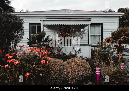 mur extérieur d'une maison en bois blanc avec un joli jardin plein de fleurs et de plantes sur une rue calme dans un village isolé, quartier ouest Banque D'Images