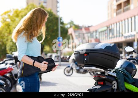 Une femme à tête rousse met une ceinture pour monter à bord d'une moto Banque D'Images