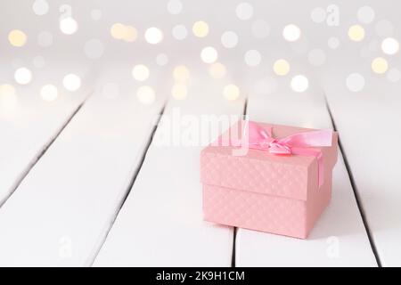 Décor romantique festif avec cadeau et cadeau rose sur table blanche avec lumières bokeh Banque D'Images