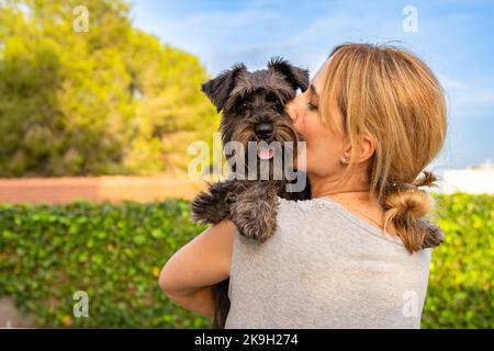 Belle femme qui embrasse et embrasse le chien. Chien et propriétaire ensemble à l'extérieur. Amour et amitié entre chien et propriétaire Banque D'Images