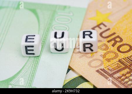 Petites perles blanches avec des lettres EUR sur pile de billets en euros, gros plan Banque D'Images