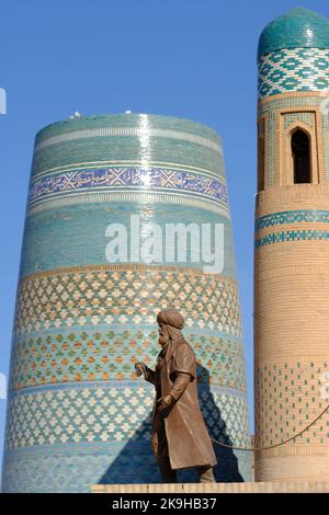 Khiva Ouzbékistan - ancien commerçant figure monument aux anciennes routes de la soie sur le site de l'UNESCO d'IInchon Qala avec le minaret de Kalta Minar en arrière-plan Banque D'Images