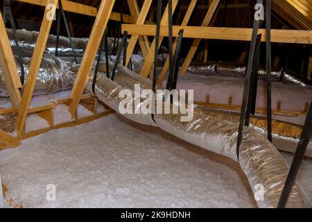 L'installation de l'isolation en laine écologique est versée dans le toit d'isolation de grenier à la maison neuve Banque D'Images