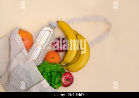 Sac en tissu écologique, épicerie, mode de vie sain. Des fruits et une bouteille d'eau dans un sac de linge. Sac à provisions en coton. Concept zéro déchet Banque D'Images