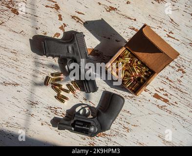 Un noir, Glock 19, 9mm, pistolet et un Ruger, 9mm, snub nez, revolver sur une table en bois avec quelques balles. Banque D'Images