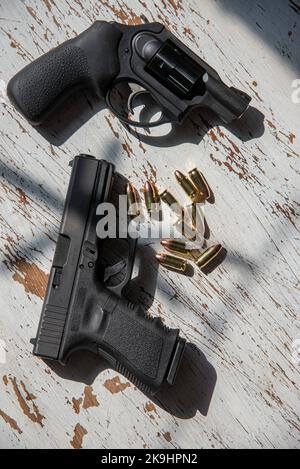 Un noir, Glock 19, 9mm, pistolet et un Ruger, 9mm, snub nez, revolver sur une table en bois avec quelques balles. Banque D'Images