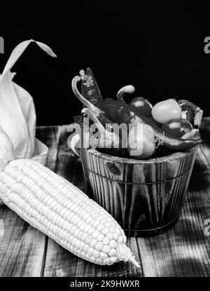 Épis de maïs avec piments et tomates légumes frais nourriture naturelle dans seau en bois, bio Banque D'Images