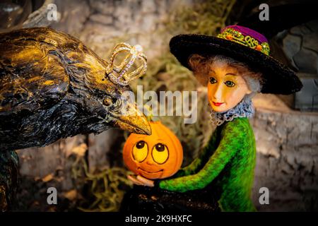 Grand corbeau noir avec couronne menace sur une jolie sorcière avec citrouille dans le décor d'Halloween secenaio-flou d'arrière-plan Banque D'Images