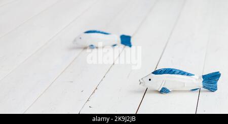 Deux poissons en bois sur le sol. Jouets artisanaux bleu et blanc sorbby pour enfants. Bannière horizontale avec espace de copie. Banque D'Images