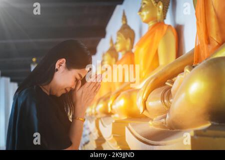 Belle femme asiatique rend hommage à la statue de Bouddha avec respect et foi Banque D'Images