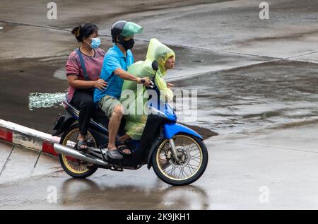 SAMUT PRAKAN, THAÏLANDE, OCT 11 2022, Une personne en imperméable est à cheval sur une moto sur une route humide Banque D'Images