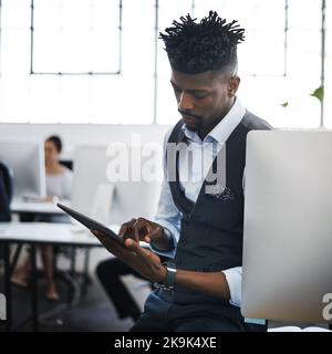 Utilisation d'une application qui met son entreprise sur la carte. Un jeune homme d'affaires utilisant une tablette numérique dans un bureau moderne. Banque D'Images