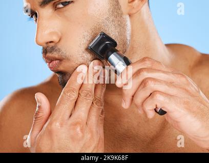 Beauté, soin de la peau et homme rasage de la barbe dans sa routine de toilettage avec une machine électrique dans un studio au Mexique. Bien-être, Latino et modèle masculin sain Banque D'Images
