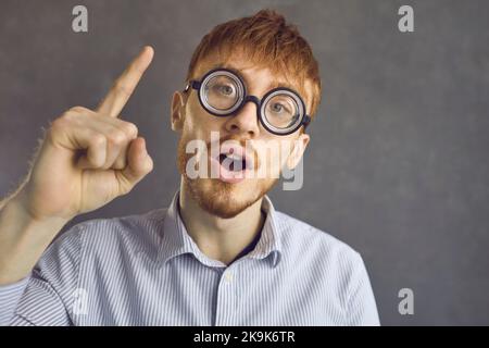 Tête rouge drôle homme en verre épais rond ayant idée solution lumineuse Banque D'Images