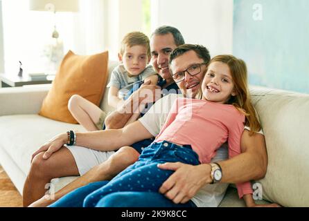 La famille est la seule chose qui compte. Portrait court d'une famille affectueuse de quatre personnes sur le canapé à la maison. Banque D'Images