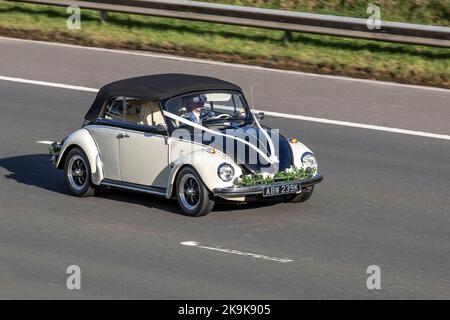 1972 70s années 70, noir et blanc Old Type VW Volkswagen Beetle, voiture de mariage décapotable à conduite à gauche avec rubans. Autrement connu sous le nom de Type 1, deux portes, moteur arrière subcompact voiture économique, Käfer, Vocho, Fusca, Cocinelle, Maggiolino, Punch Buggy, voiture populaire allemande, refroidissement par air, moteur arrière, Voiture compacte à propulsion roulant sur l'autoroute M6, Royaume-Uni Banque D'Images