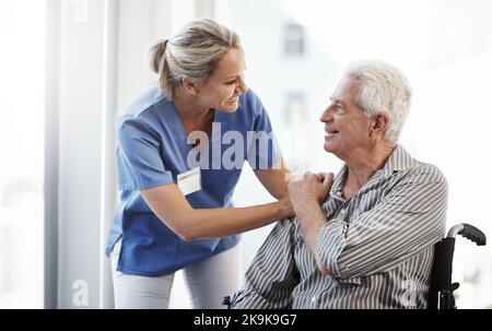 Vous semblez faire beaucoup mieux aujourd'hui. Une infirmière de sexe mûr et son patient de sexe masculin en fauteuil roulant sont à l'hôpital. Banque D'Images