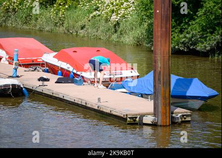 Hambourg, Allemagne. 11th juin 2022. Un homme se tient devant un bateau à moteur couvert et rend son propre bateau à nouveau digne de la route. Credit: Jonas Walzberg/dpa/Alay Live News Banque D'Images