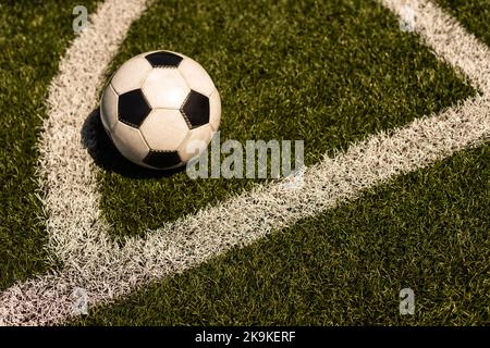 ballon de football blanc et noir sur fond d'herbe verte et de stade. idée de paris sportifs. Banque D'Images