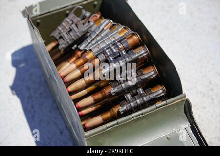 Gros plan d'une courroie de mitrailleuse chargée de cartouches, dans une boîte de munitions. Banque D'Images