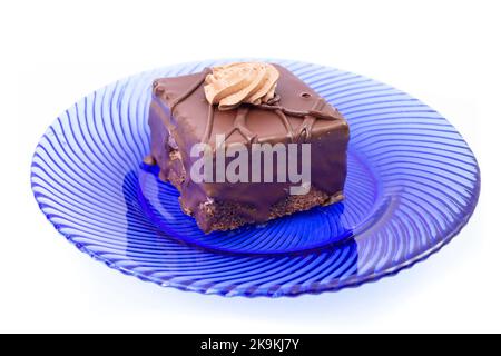 Gâteau Amandine, portion carrée, sur une assiette en verre bleu, gros plan isolé sur fond blanc Banque D'Images