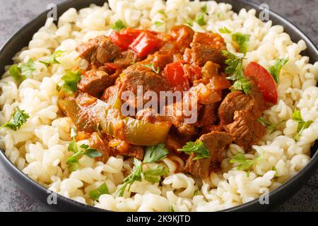 Porkolt est un ragoût hongrois avec de la viande désossée, du paprika et quelques légumes servis avec des nouilles aux oeufs Nokedli sur l'assiette de la table. Horizon Banque D'Images