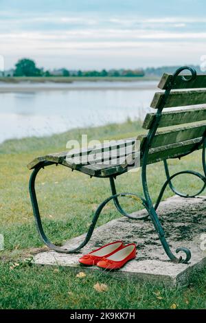 Paire de chaussures rouges et banc de stationnement. Banque D'Images