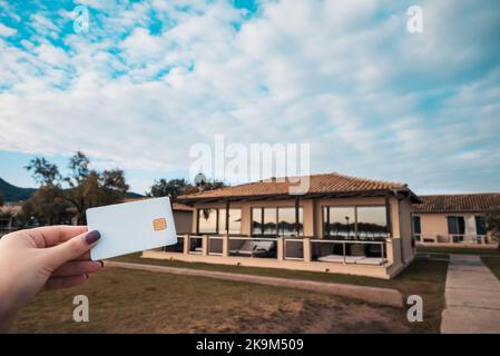 Carte de banque blanche dans la main de femme sur le fond de l'hôtel Bungalow à Moraitika, Corfou, Grèce. Le concept de paiement pour Relax et Unlimited Banque D'Images