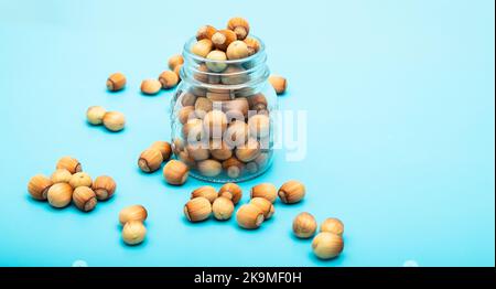 Noisette dans un pot. Beaucoup de noisettes. Banque avec écrous sur fond bleu Banque D'Images