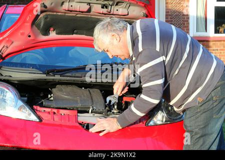 Mécanicien travaillant une voiture. À l'aide d'une clé sur le moteur. Banque D'Images