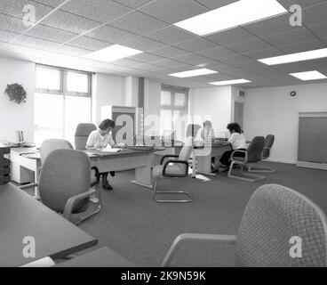 1989, historique, un homme et une femme travaillant à leurs bureaux dans un grand bureau ouvert, Angleterre, Royaume-Uni. Grands bureaux semi-circulaires avec chaises environnantes pour les réunions informelles - dont l'un a lieu - et ordinateurs personnels de l'époque en démonstration. Banque D'Images