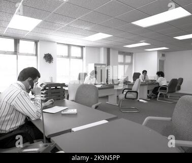 1989, employés historiques, hommes et femmes travaillant à leur bureau dans un grand bureau ouvert, Angleterre, Royaume-Uni. De grands bureaux semi-circulaires avec chaises environnantes pour des réunions informelles - un en cours - et des ordinateurs personnels de l'époque peuvent être vus. Banque D'Images