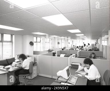 Fin 1980s, historique, deux femmes travaillant dans des bureaux dans une cabine partagée, avec d'autres cabines partagées dans l'étage de bureau, dans une installation de travail commune à cette époque, Angleterre, Royaume-Uni. Vu dans l'image, les ordinateurs personnels, y compris un IBM. Banque D'Images