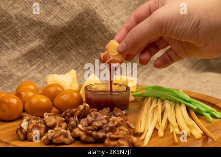 Quelqu'un trempent un morceau de fromage dans le miel sur un fond de variétés variées de fromage Banque D'Images