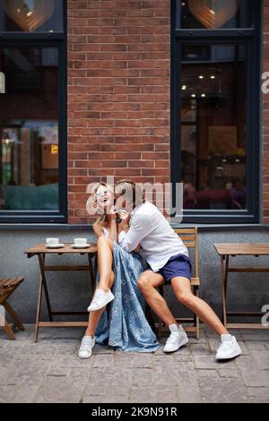 Homme à la mode et femme attrayante buvant un café dans un café de la rue et de Amuse-toi bien. Couple est heureux de jouer. Le mannequin riait à long terme Banque D'Images