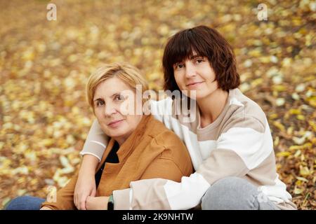 Mère caucasienne et sa fille assise dans un parc d'automne. Portrait de la mère sénior et de la fille gaie adulte passant du temps ensemble à l'extérieur dans le parc en saison de chute. Photo de haute qualité Banque D'Images