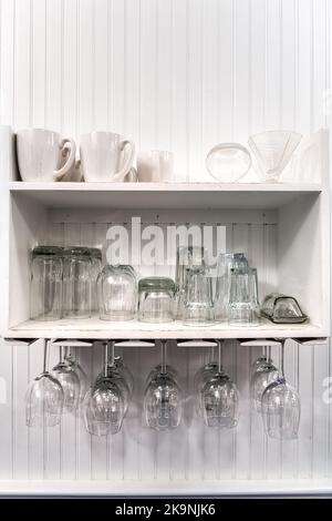 Gros plan de cuisine moderne intérieur design blanc armoire étagères avec tasses blanches, à l'envers suspendu porte-verres à vin vide pour le rangement Banque D'Images