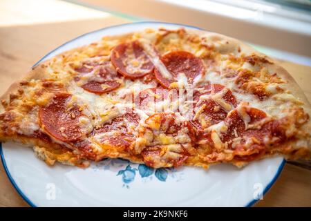 Macro-gros plan de pizza fraîche à croûte mince sur plaque blanche avec fromage mozzarella fondu, tranches de viande de pepperoni d'aliments gras malsains Banque D'Images