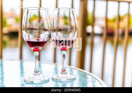 Deux verres de vin rouge français coulé Cotes du Rhone sur un balcon en verre à Miami, Floride avec vue Banque D'Images