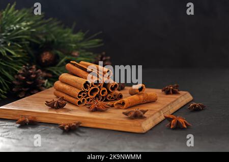Bâtonnets de cannelle parfumés avec anis sur un panneau en bois sur fond noir. Composition de Noël Banque D'Images