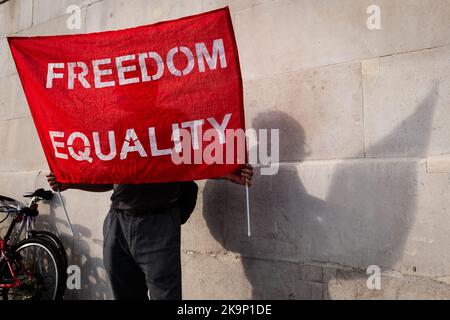 Londres, Royaume-Uni. 29 octobre 2022. Un homme tient une bannière rouge disant Freedom Egalité, son corps silhoueté sur le mur derrière. Protestation contre l'Iran. Banque D'Images