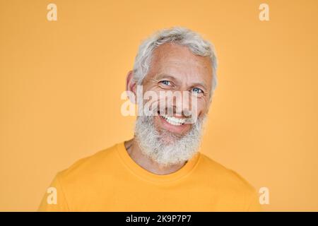 Homme barbu plus vieux souriant isolé sur fond jaune, portrait de tête. Banque D'Images