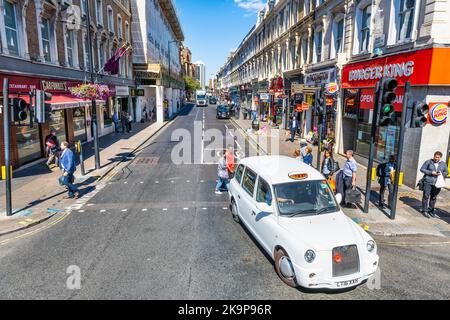 Londres, Royaume-Uni - 22 juin 2018: Vue grand angle de beaucoup de petits magasins boutiques restaurants à Paddington, Londres Royaume-Uni, les gens en taxi blanc Banque D'Images