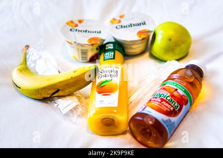 Key West, Etats-Unis - 25 janvier 2021: Kimpton Hotel matin helathy petit déjeuner de fruits de pomme, jus d'orange de banane et yaourt sans gras de Chobani sur le lit de la chambre Banque D'Images