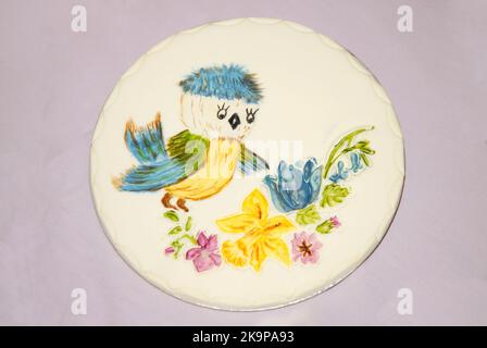 Plaque décorative pour sugarcraft pour gâteaux ou autres occasions festives, montrant un oiseau avec une tête bleue et des ailes regardant des fleurs Banque D'Images
