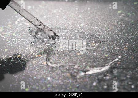 Dégradé. Rétroéclairage. Pipeter avec du sérum ou du gel sur fond noir avec paillettes. Acide hyaluronique hydratant. Gel antibactérien. Cosmétologie. Eau. Banque D'Images