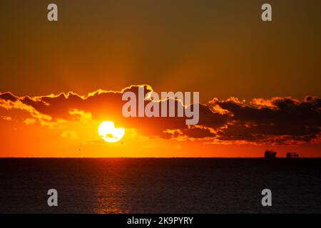 Le soleil de l'aube se couche derrière le nuage au-dessus de l'horizon marin à l'aube. Rayons de soleil. Lever du soleil sur la mer. Silhouettes noires de mer et de nuages. Ciel mer paysage. Seascape des nuages en mouvement rapide Banque D'Images